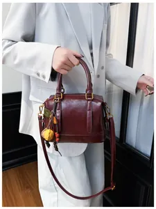 Detail of dark red leather Boston bag with gold hardware and colorful leaf pendant