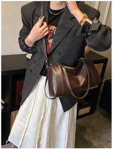 Détail du sac Boston marron foncé en cuir avec bandoulière porté par un mannequin