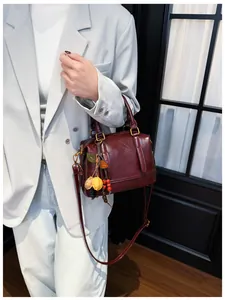 Detail of burgundy leather Boston bag with leaf pendant charm shown on a fashion model