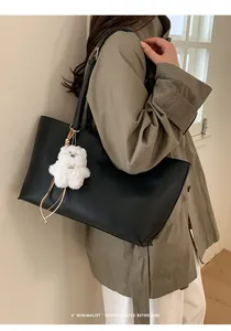 Detail shot of black faux leather tote bag with cute white teddy bear plush charm
