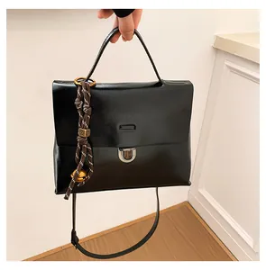 Detail der schwarzen Lackleder-Tasche mit silbernem Schloss und geflochtenem Anhänger