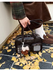 Détail du sac à bandoulière en PU brillant marron foncé avec deux poches et ours