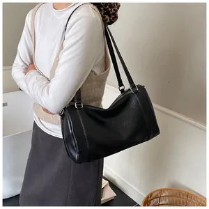 Détails d'un sac Boston noir brillant en forme de baril avec une texture cuir élégante
