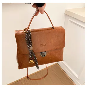 Detailansicht eines braunen Lederrucksacks mit goldener Schnalle und gewebtem Anhänger
