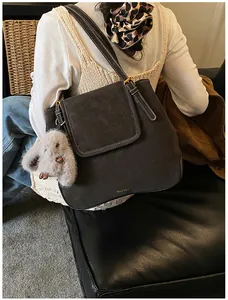 Detail of dark grey suede tote bag with white contrast stitching and plush bunny pendant
