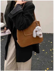 Detail of brown matte tote bag with gold lettering and a cute grey bunny plush charm