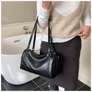 Gros plan sur la texture du cuir noir et les anneaux en argent du sac Boston