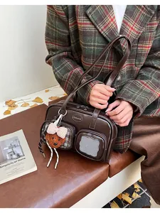 Détail d'un sac porté épaule en cuir PU marron foncé avec poches et breloque ours