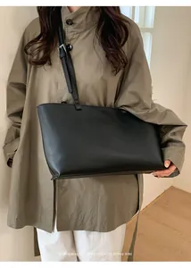 Detail of minimalist black large capacity PU leather tote bag with elegant shoulder straps
