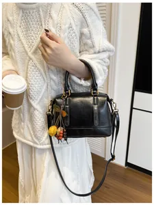 Detail of black Boston bag with gold hardware and colorful decorative pendant