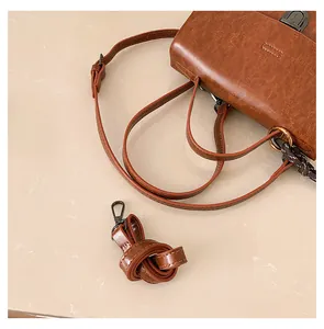 Details einer braunen Retro-Ledertasche mit verstellbarem Schultergurt und Metallschnalle