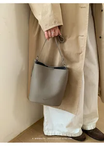 Detail showing grey pebbled leather texture and brand logo on a chic bucket bag