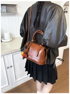 Detailed view of a vintage brown leather Boston bag worn as a crossbody purse