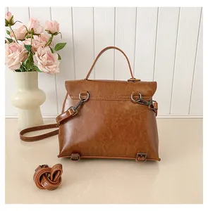 Detailansicht der braunen Vintage-Tasche mit D-Ringen und Metallfüßen auf der Rückseite