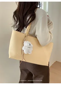 Detail of soft cream PU leather tote bag with a cute plush bear charm and heart tag