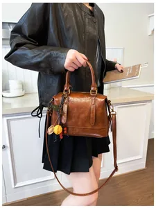 Detail view of dark brown oil-wax leather Boston bag with bohemian bead charm and strap