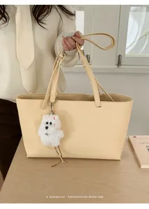 Detail of minimalist cream PU leather tote bag featuring a cute white plush charm