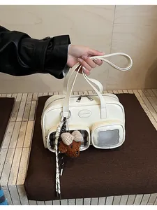 Détail du sac oreiller en similicuir blanc avec pendentif ours et poches texturées