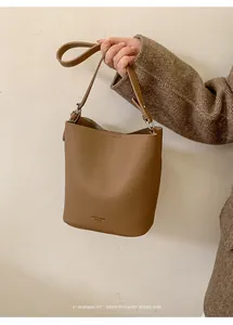 Close-up of brown pebbled leather bucket bag featuring elegant gold brand lettering
