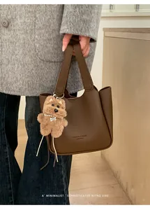 Détail du sac seau marron vintage avec motif litchi et pendentif chien en peluche