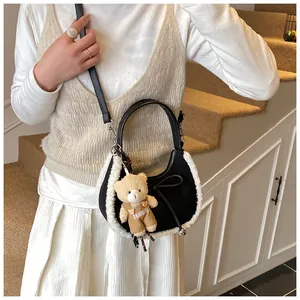 Detail of black suede crescent bag with plush shearling trim and cute bear charm