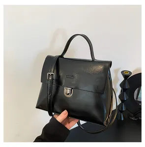Detail einer schwarzen Lackleder-Handtasche im Vintage-Stil mit Metallverschluss