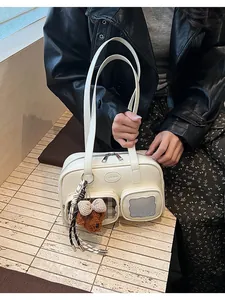 Détail d'un sac oreiller blanc crème avec poche filet et charm d'ours en peluche