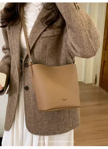 Brown leather bucket bag with long strap shown on model with vintage style coat