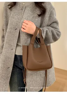 Vue détaillée du sac seau en cuir marron foncé avec grain litchi et logo gravé
