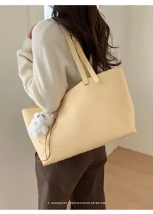 Minimalist large pale yellow tote bag with bear charm shown in a cozy indoor setting