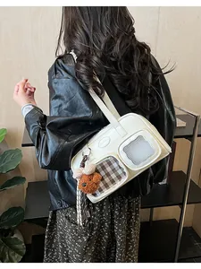 Détail du sac à bandoulière en cuir blanc avec poches et pendentif ours en peluche