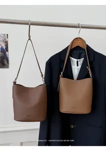 Detailed view of bucket bags in brown and tan with adjustable straps and lychee texture