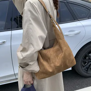 Caramel suede hobo bag with wide shoulder strap shown in an outdoor street style shot