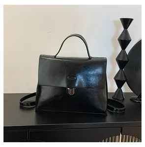 Vorderansicht einer eleganten schwarzen Lackleder-Umhängetasche mit silberner Metallschnalle