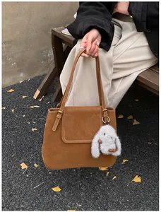 Close-up of brown suede tote bag with a white rabbit plush charm and fine stitching