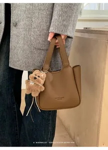 Détail du sac seau rétro marron avec texture litchi et pendentif de chien en peluche