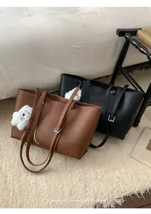 Detail of minimalist PU leather tote bags in brown and black with plush pendant