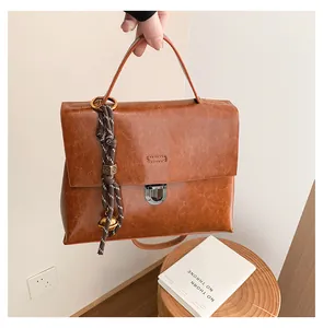 Detail einer braunen Kunstleder-Handtasche im Vintage-Stil mit geflochtenem Griff