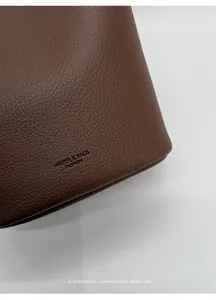 Close-up of brown litchi pattern leather and embossed logo on the shoulder bag