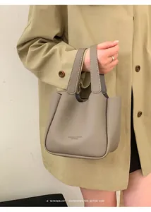 Détail de la texture cuir grainé et des coutures sur la poignée du sac fourre-tout taupe