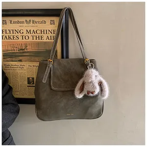 Detail of vintage olive bucket bag with contrast stitching and plush rabbit charm