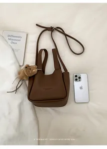 Détails du sac seau en cuir marron foncé avec texture litchi et charmant petit ours