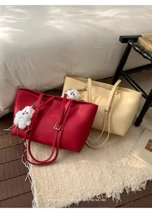 Detail of red and beige large PU leather tote bags with cute plush dog pendants