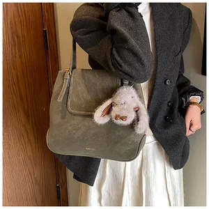 Detail view of a retro dark green bucket bag with a cute plush bunny charm on a model