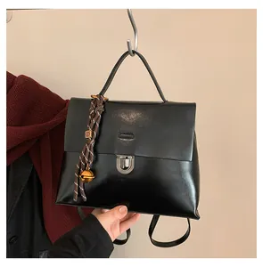 Detailansicht der schwarzen Vintage-Ledertasche mit Metallschnalle und Glockenanhänger