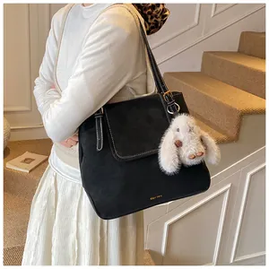 Detail of black large-capacity tote bag in textured matte leather with a cute white bunny charm