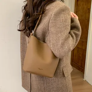 Chic camel leather bucket bag styled with a winter herringbone coat for office look