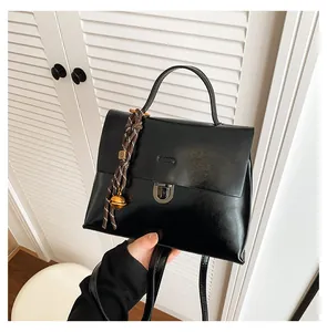 Detail der schwarzen Messenger-Tasche mit gewebtem Anhänger und silberner Schnalle