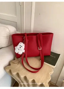Detail of red large capacity tote bag with lychee texture and plush dog pendant