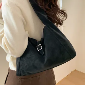 Minimalist black suede shoulder bag with silver buckle detail shown on a model